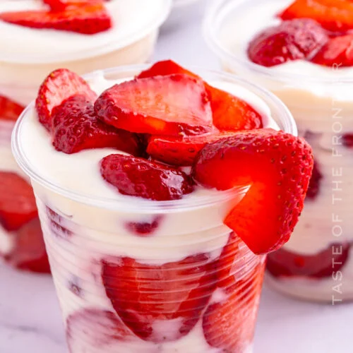 Cups filled with creamy yogurt and fresh strawberry slices.