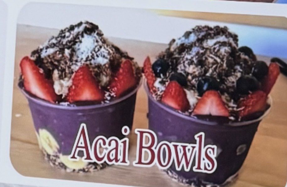 Two acai bowls topped with strawberries and granola.
