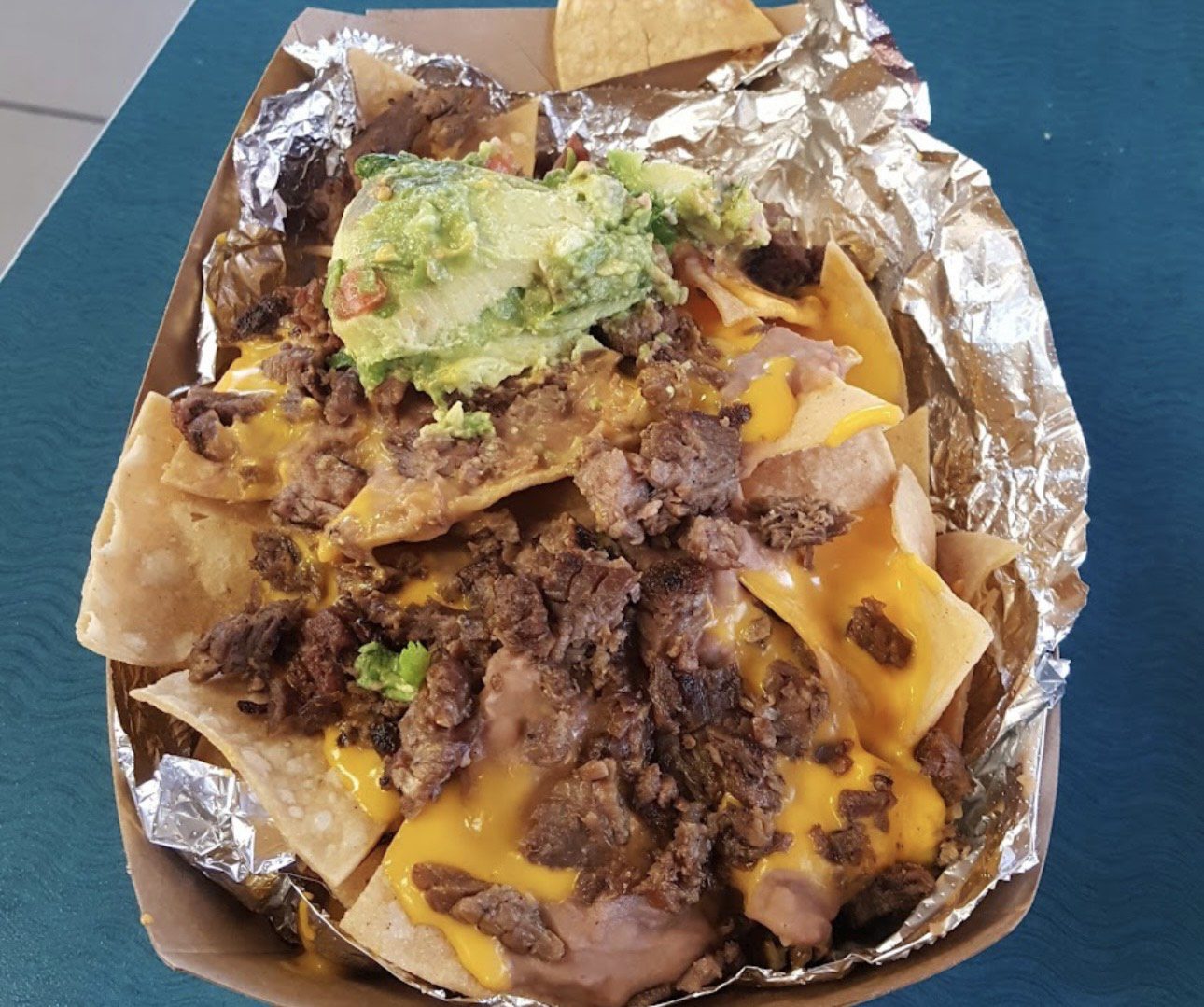 Loaded nachos topped with seasoned beef, melted cheese, and guacamole.