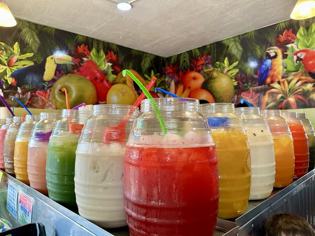 Colorful fresh fruit juices in clear jars with straws display.