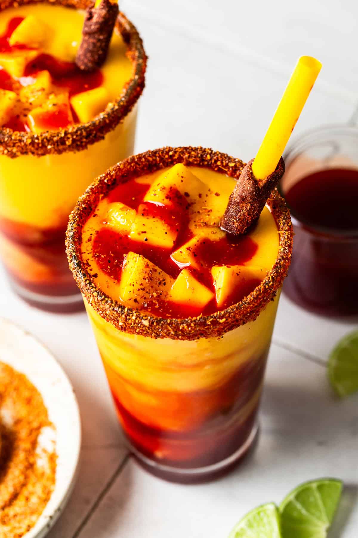 A vibrant mango chili drink with mango chunks and a spicy rim.